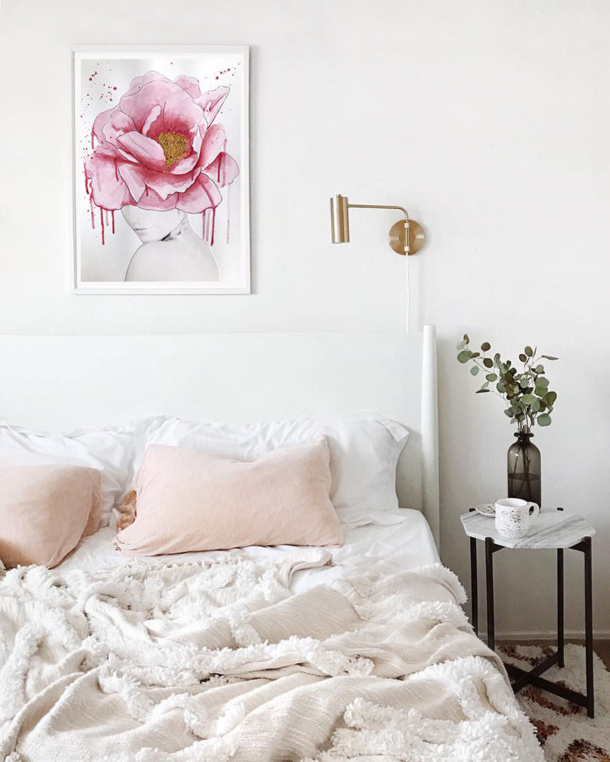 Feminine bedroom with white and pink bedding and floral artwork on the wall.